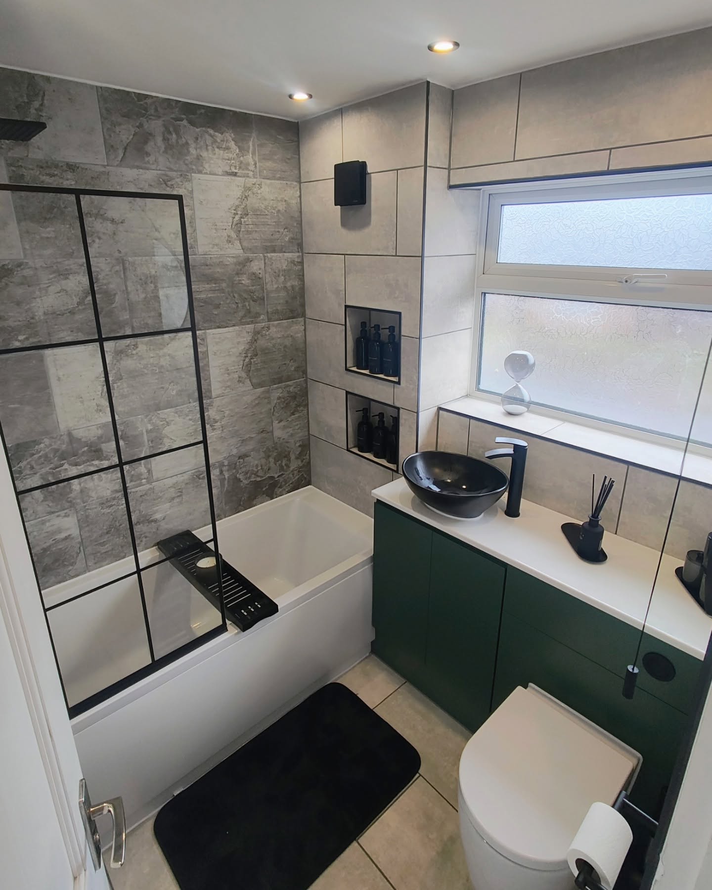 New bathroom with stone tiles and green and white cabinets