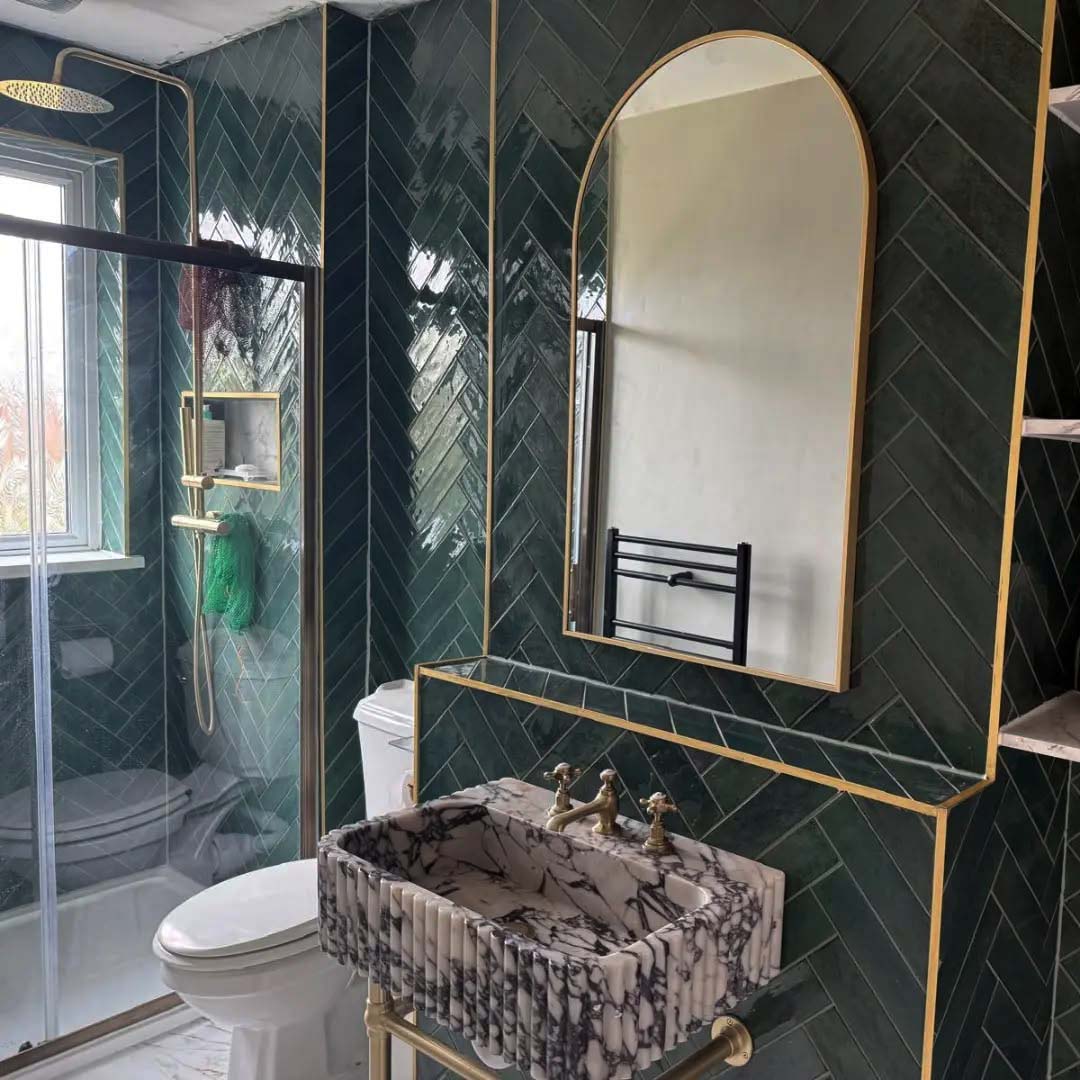 Green wall tiles in bathroom with gold trim